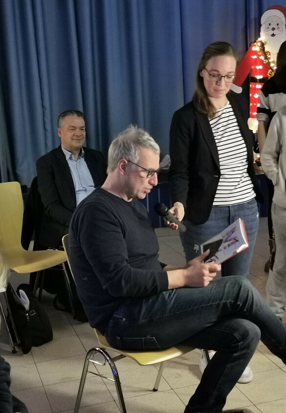 Marco Bode liest eine Geschichte vor. Frau Granig hält das Mikrofon