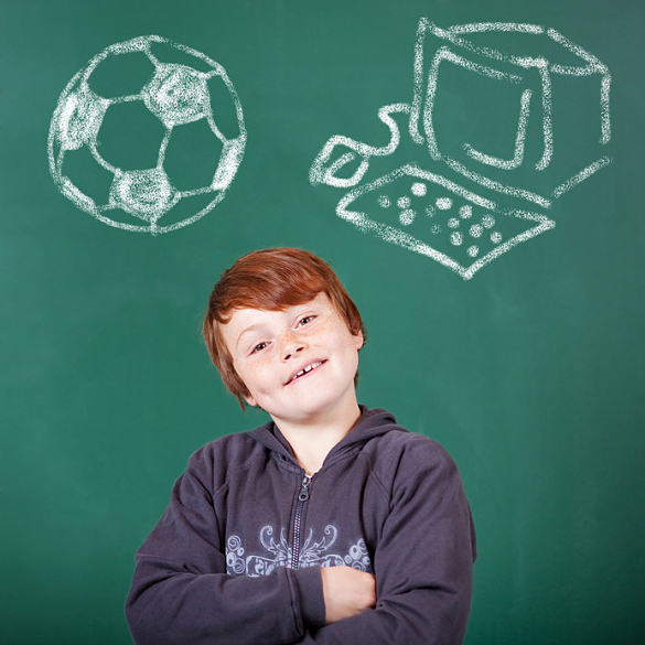 das Foto zeigt einen Jungen vor einer Tafel. Auf der Tafel wurde mit Kreide ein Fußball und ein Bildschirm mit Tastatur gemalt.