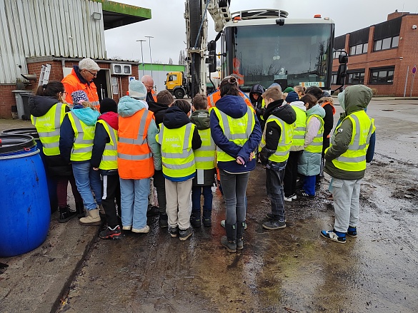 Kinder in Warnwesten stehen vor einem Fahrzeug der Bremer Straßenreinigung.